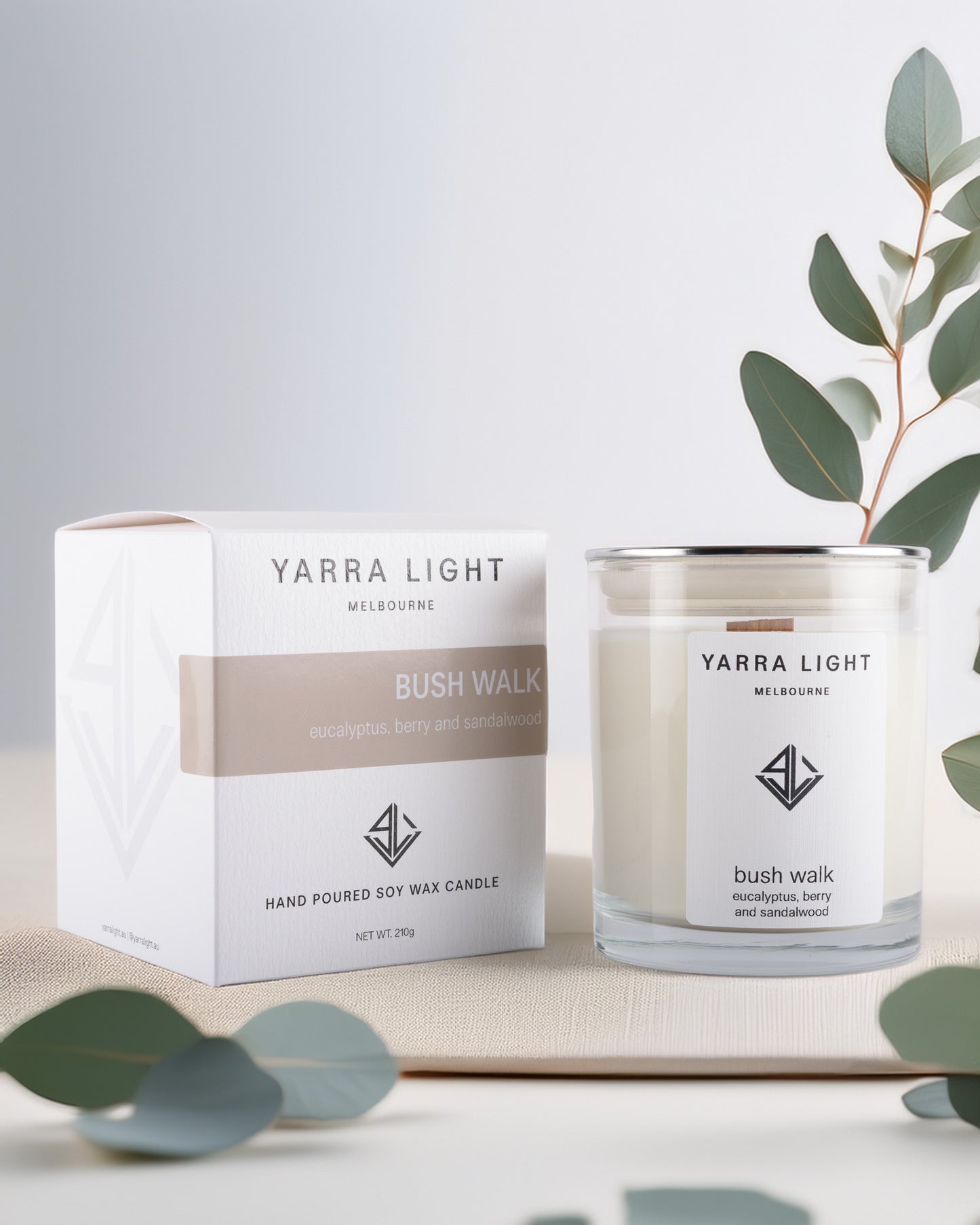 Yarra Light soy wax candle and packaging on a light background with eucalyptus leaves.
