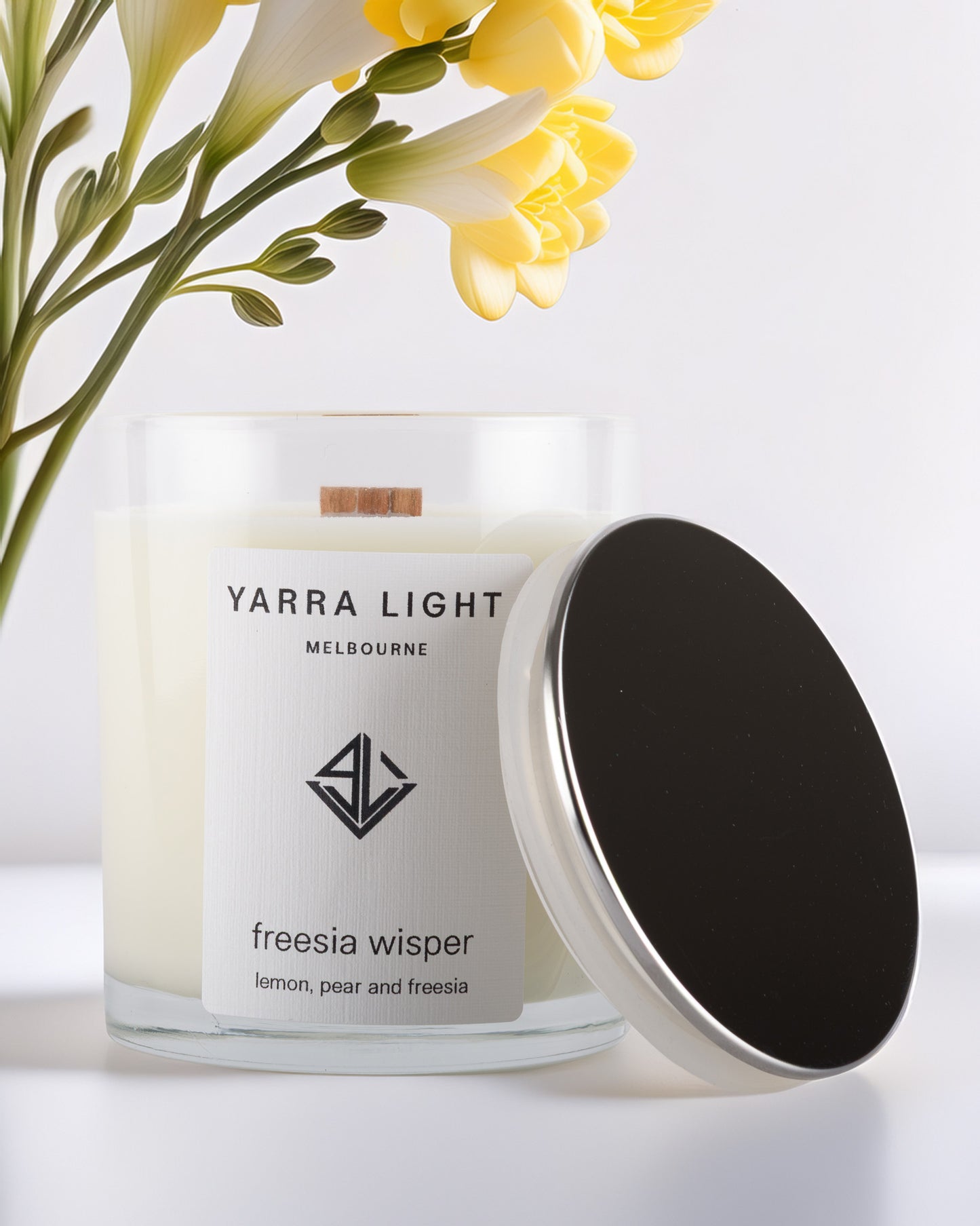 Yarra Light soy wax candle with a silver lid and freesia flowers in the background