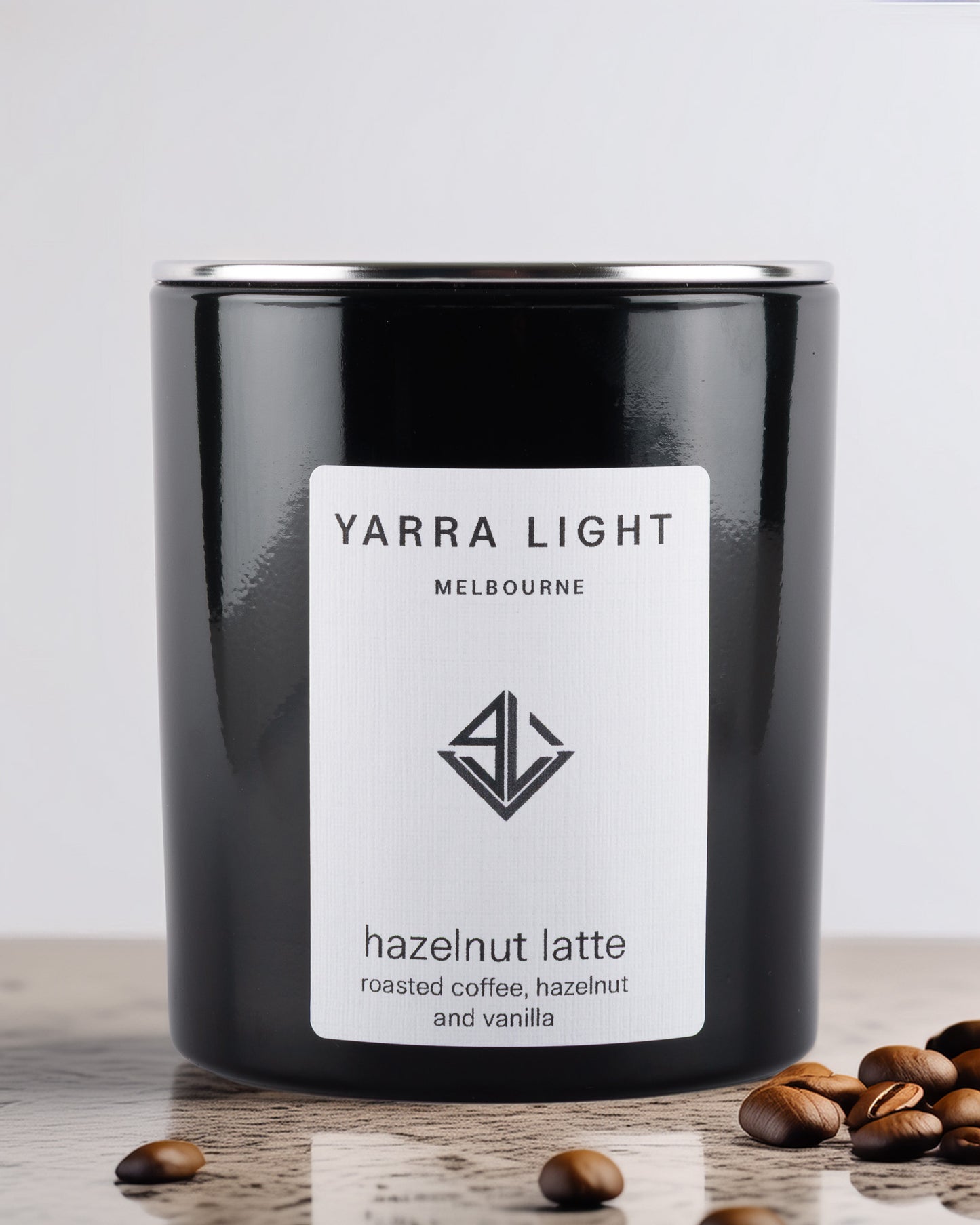Black glossy soy wax candle with 'Yarra Light Melbourne' label on a wooden surface with coffee beans.