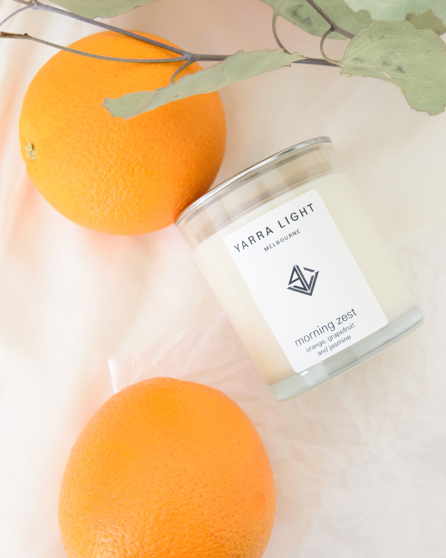 Yarra Light soy wax candle with oranges and leaves on a light background