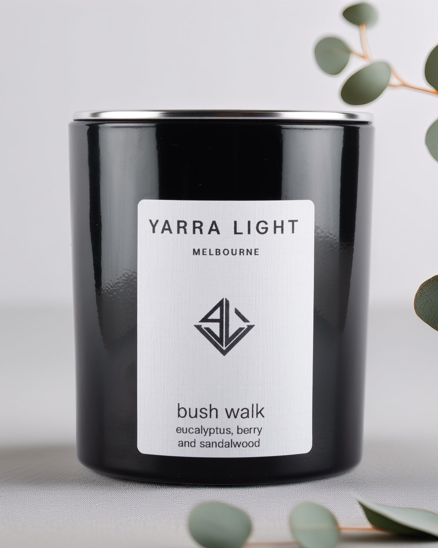 Yarra Light black glossy soy wax candle on a light background.