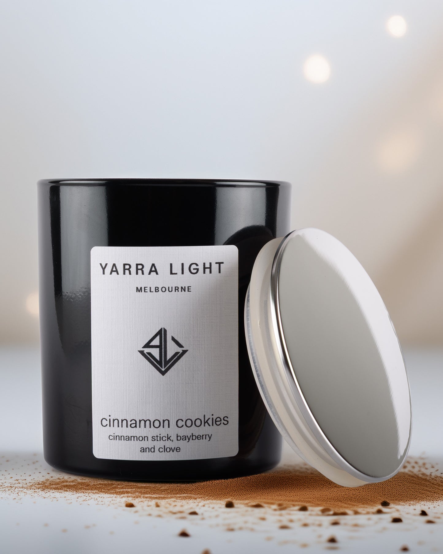 Black glossy candle jar with white label featuring 'Yarra Light' on a wooden surface.