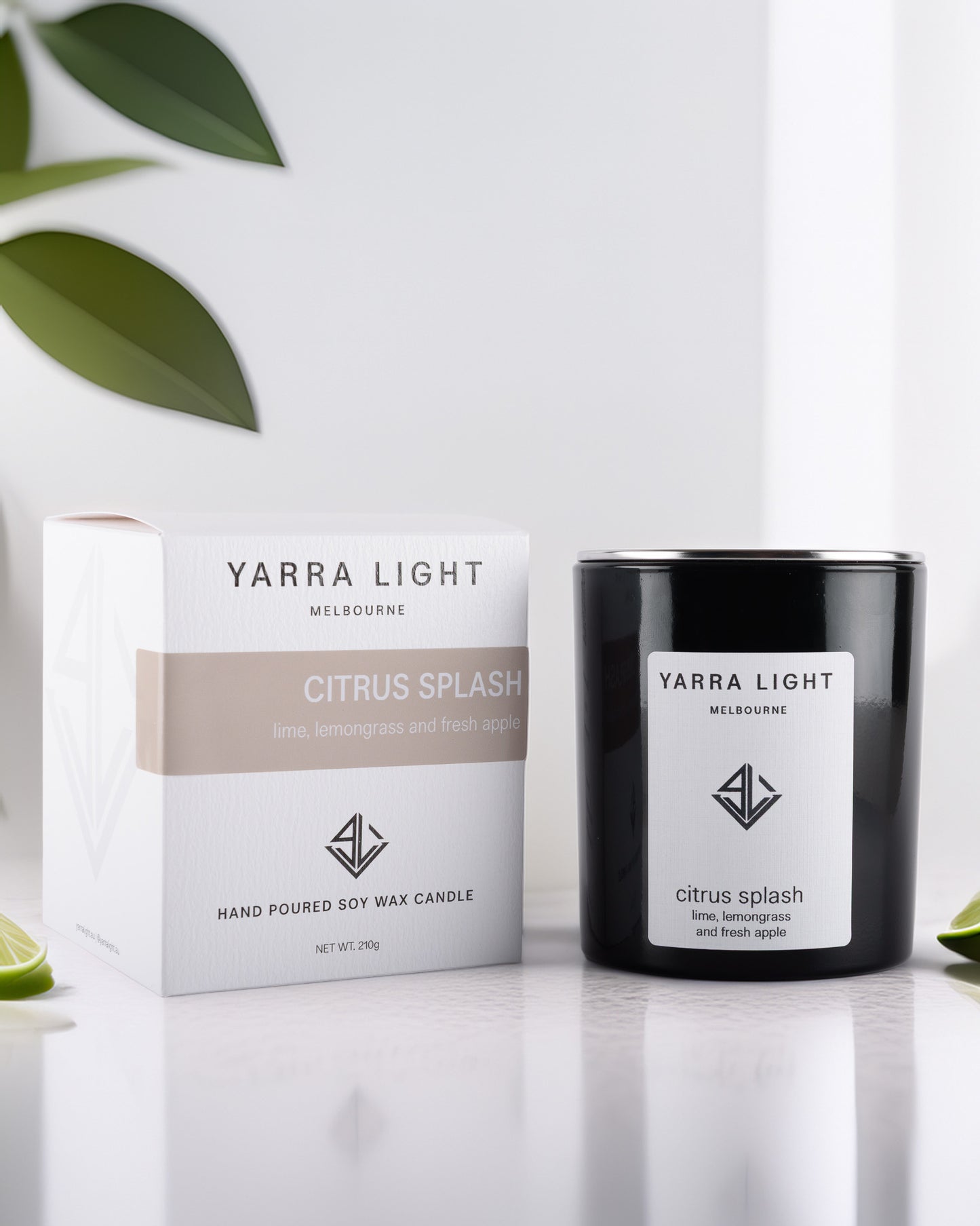 Yarra Light Citrus Splash soy wax candle and packaging on a white background with green leaves.