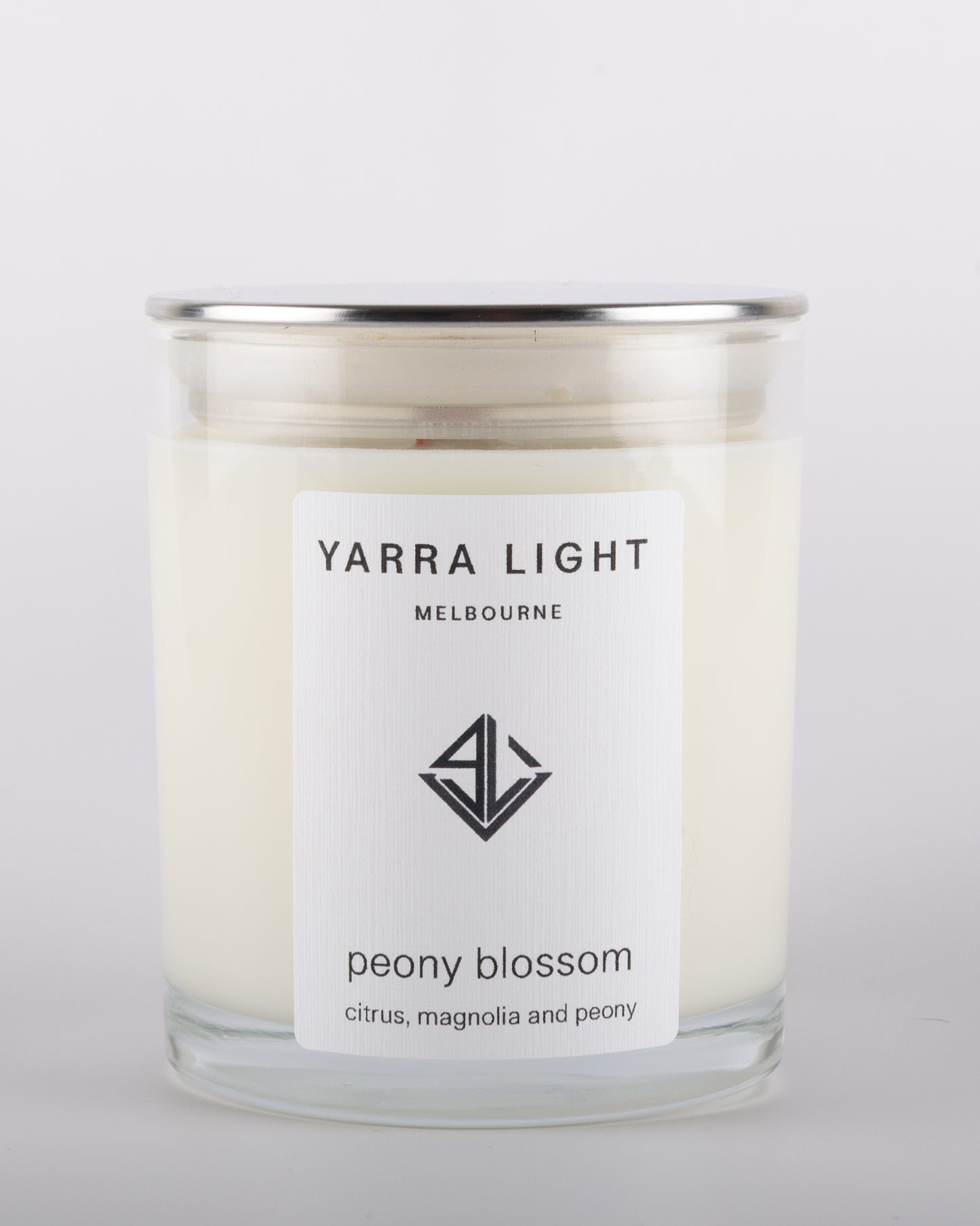 Peony Blossom soy wax scented candle with wood wick in a clear glass jar with minimalist label, inspired by the delicate and romantic fragrance of blooming peonies.