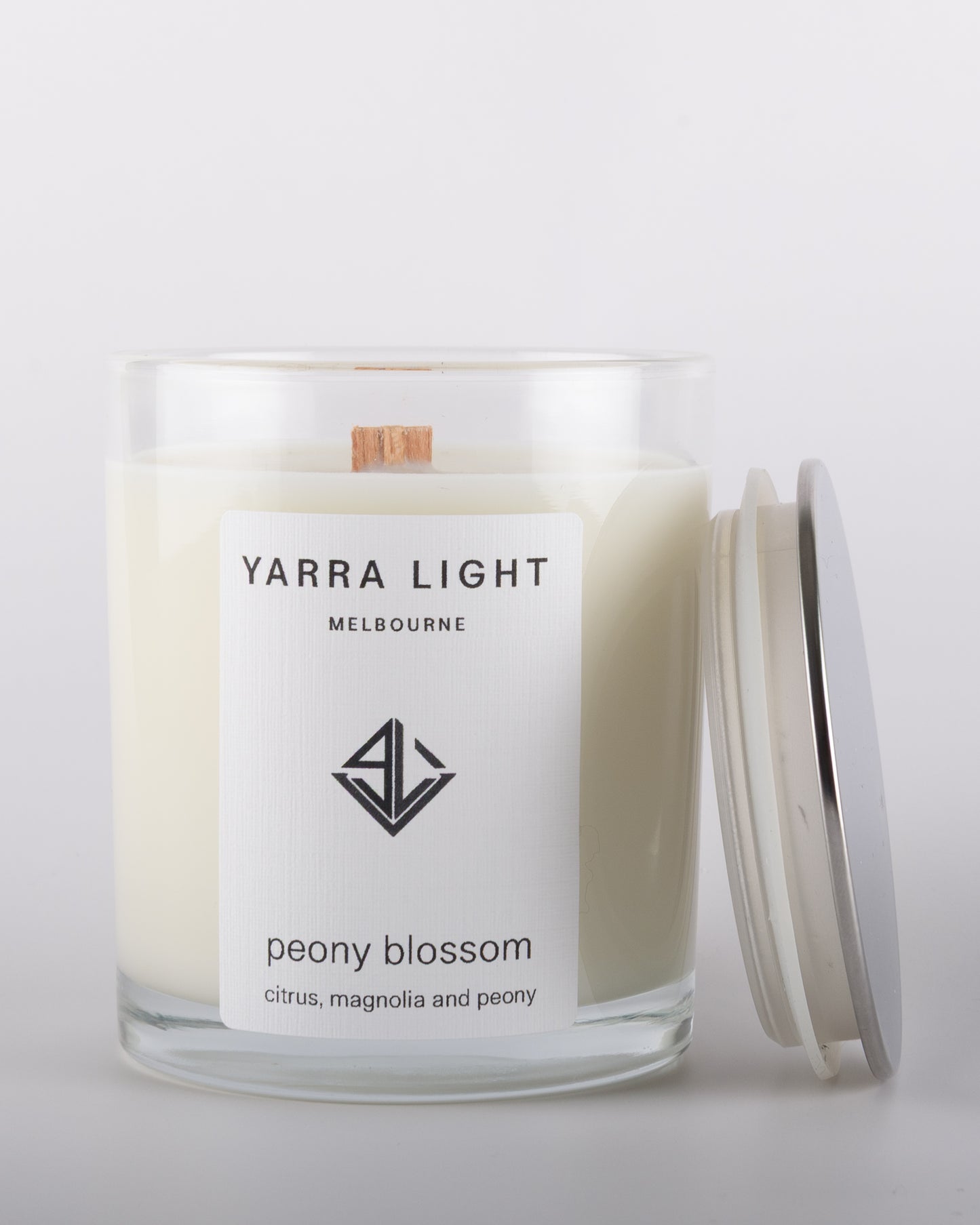 Peony Blossom soy wax scented candle with wood wick in a clear glass jar with minimalist label, inspired by the delicate and romantic fragrance of blooming peonies.