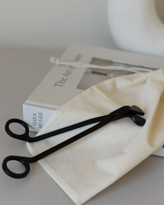 Black metal wick trimmer placed inside a reusable bag, ideal for candle care and maintenance.