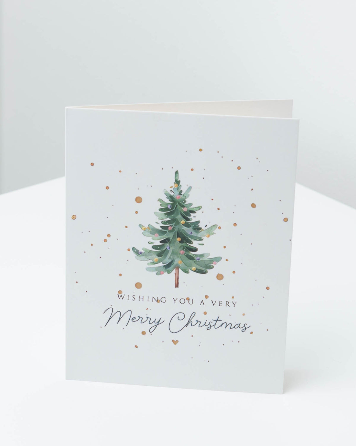 Christmas card with a green watercolour Christmas tree and gold dots, reading Wishing you a very Merry Christmas