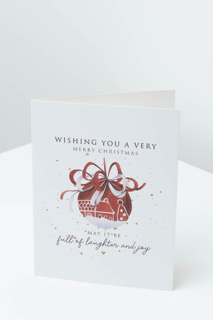 Christmas card with a red bauble tied with a ribbon bow, reading Wishing you a very Merry Christmas, may it be full of laughter and joy