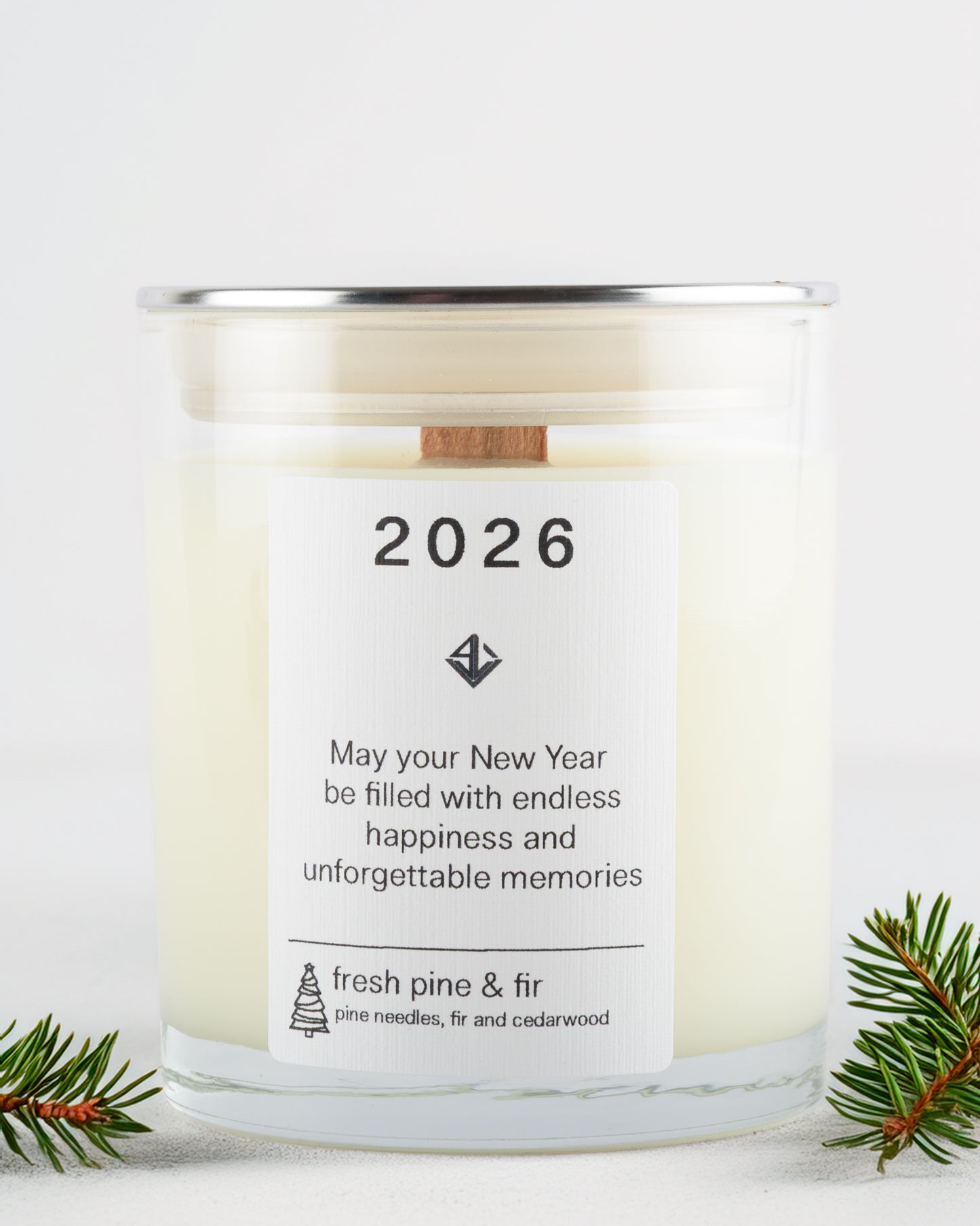 Candle with a label for the year 2026, surrounded by pine branches on a white background