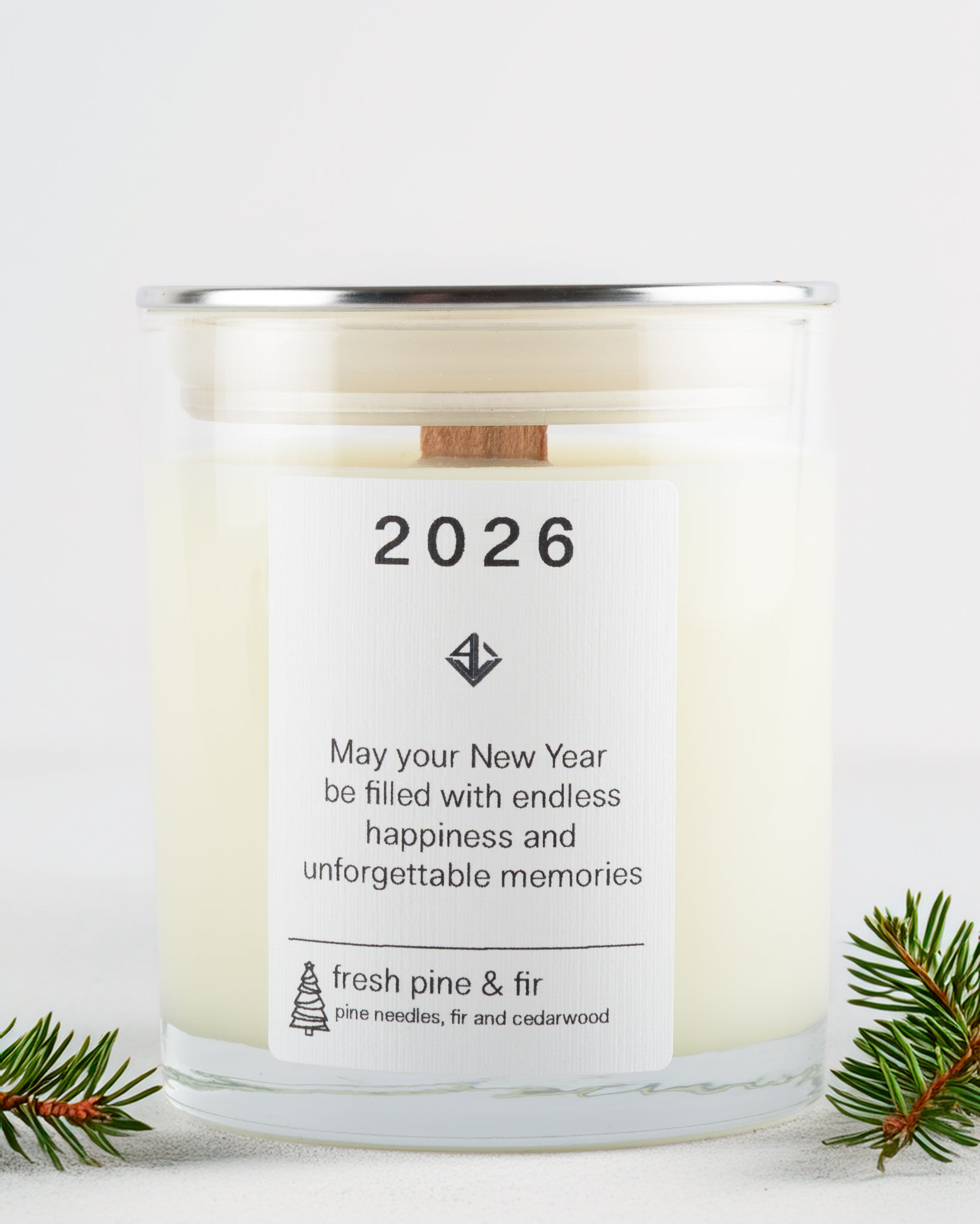 Candle with a label for the year 2026, surrounded by pine branches on a white background