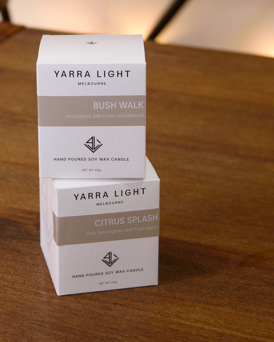 Two Yarra Light candle boxes stacked on a wooden surface, showcasing their elegant, eco-conscious packaging."