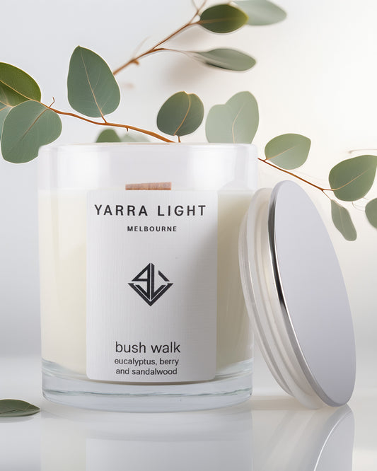 Yarra Light soy wax candle with a branch of eucalyptus leaves on a light background