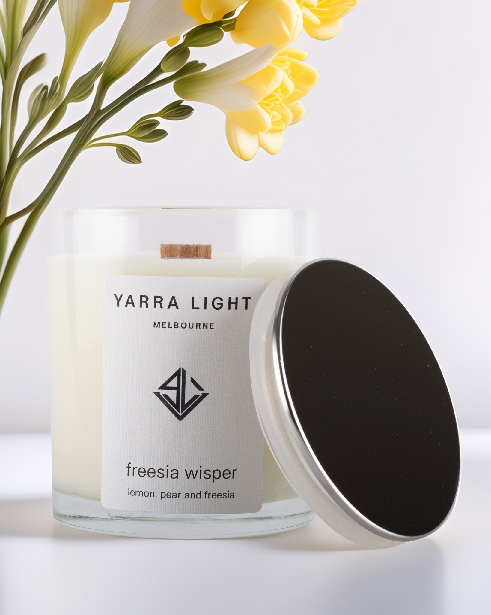 Yarra Light soy wax candle with a silver lid and freesia flowers in the background