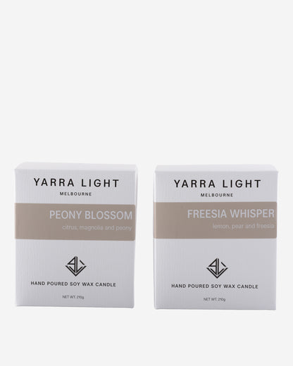 Two Yarra Light candles boxes, one labeled 'Peony Blossom' and the other 'Freesia Whisper', on a white background.