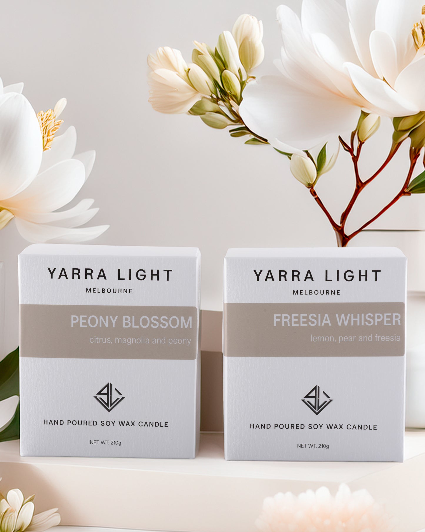 Two Yarra Light candles in boxes with flowers in the background