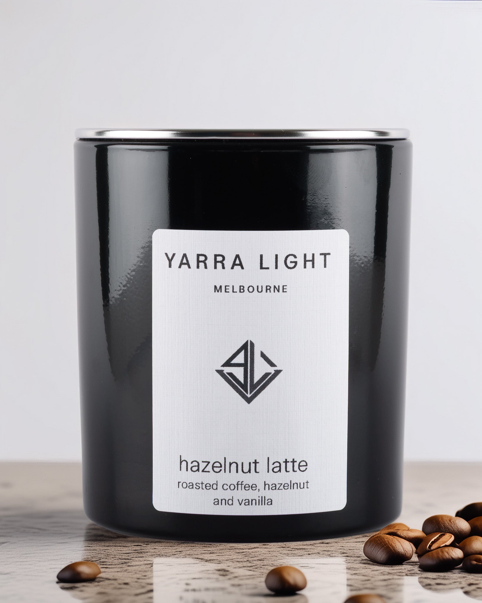 Black glossy soy wax candle with 'Yarra Light Melbourne' label on a wooden surface with coffee beans.