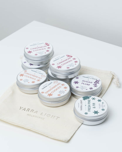 Eight mini Christmas soy candle tins: Cinnamon Cookies, Gingerbread Cookies, Sugar Plum and Fresh Pine & Fir on a Yarra Light cotton pouch