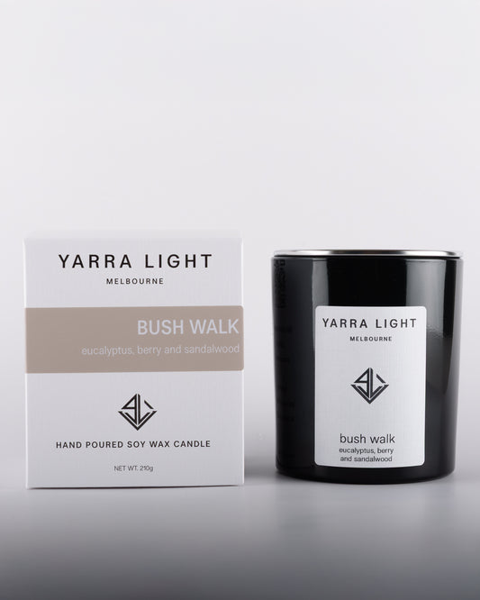 NOIR Bush Walk soy wax scented candle in a black glossy glass jar with minimalist label, positioned next to its eco-friendly packaging, inspired by Australian bushland.