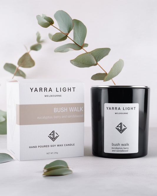 Yarra Light soy wax candle and packaging with eucalyptus leaves on a light background