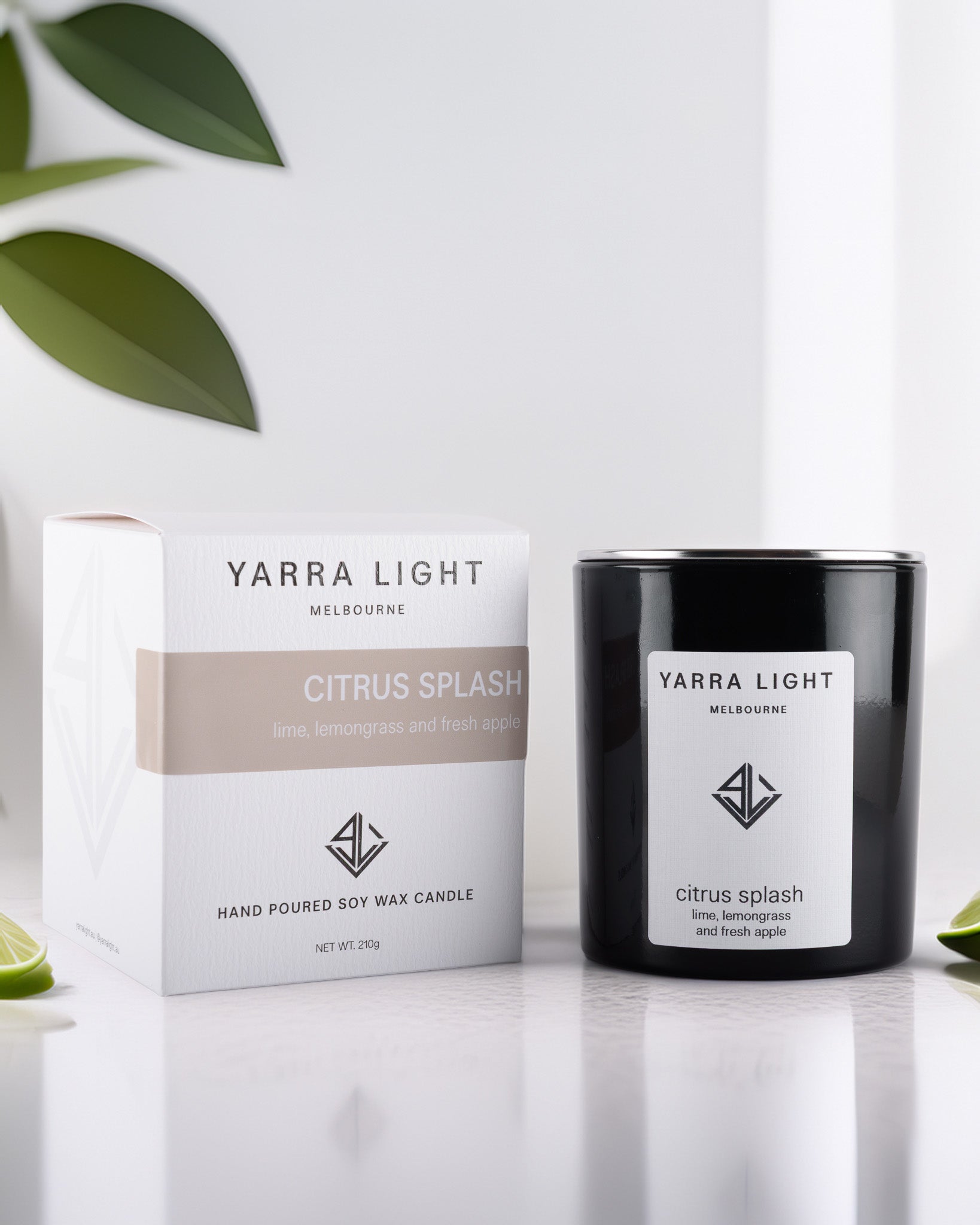 Yarra Light Citrus Splash soy wax candle and packaging on a white background with green leaves.