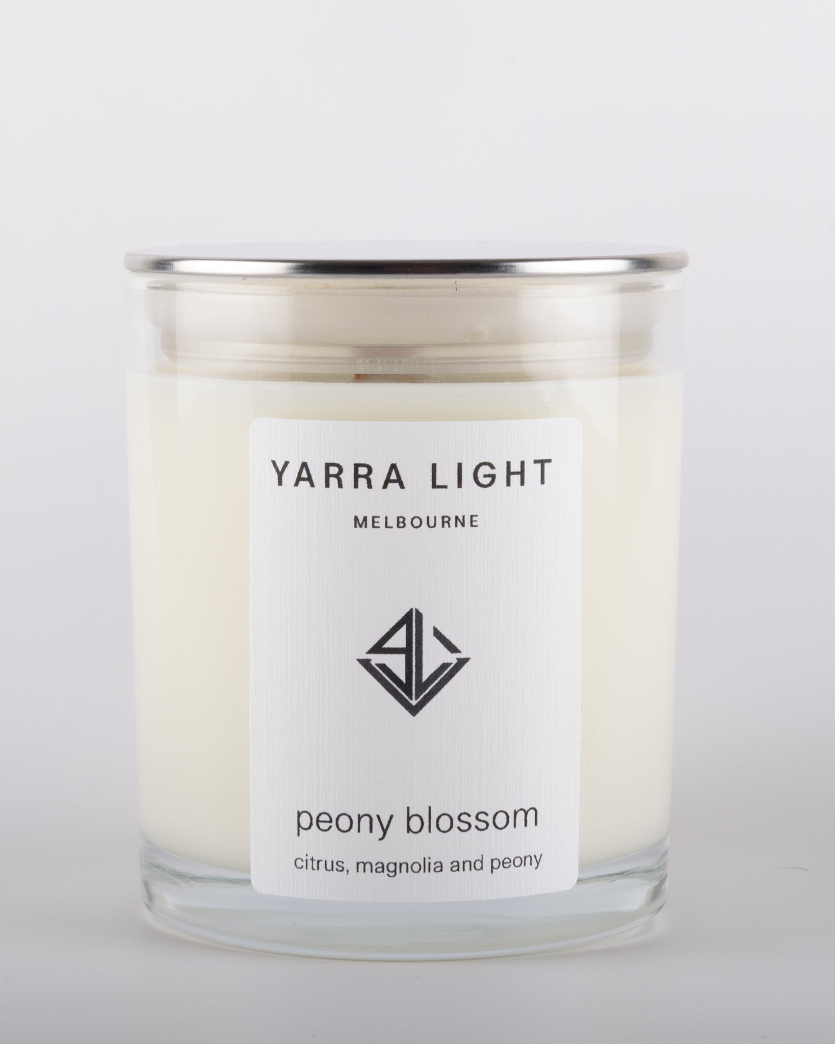 Peony Blossom soy wax scented candle with wood wick in a clear glass jar with minimalist label, inspired by the delicate and romantic fragrance of blooming peonies.
