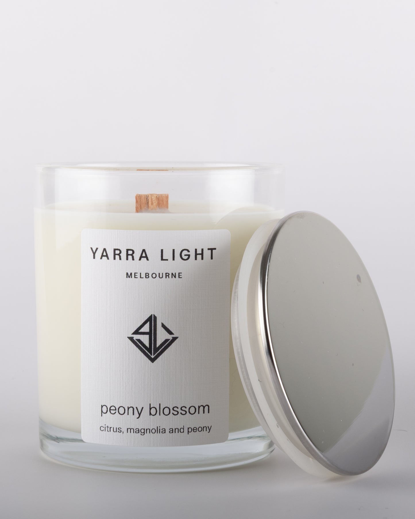 Peony Blossom soy wax scented candle with wood wick in a clear glass jar with minimalist label, inspired by the delicate and romantic fragrance of blooming peonies.