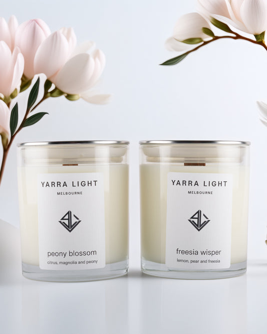 Two Yarra Light soy wax candles with floral arrangement on a light background