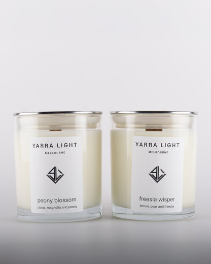Bundle featuring Freesia Whisper and Peony Blossom soy wax scented candles with wood wicks in clear glass jars with minimalist labels, inspired by blooming freesia, sweet pear, and romantic peony fragrance notes.