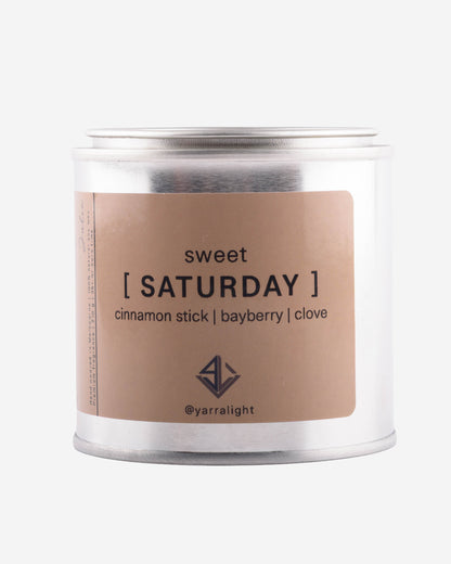 Hand poured soy wax scented candle labeled 'sweet saturday' on a white background