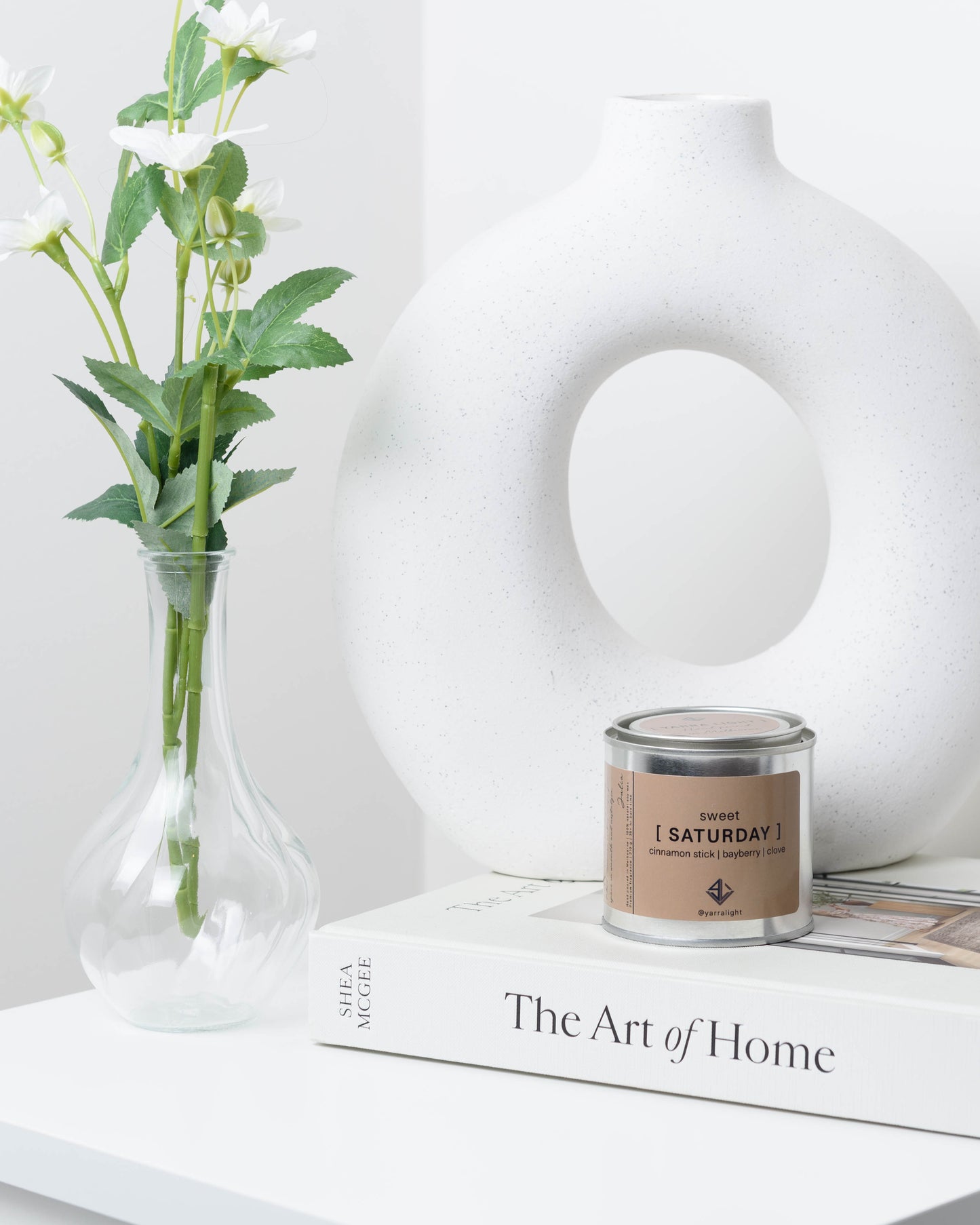 Soy wax candle with on a book next to a vase.