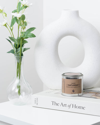 Soy wax candle with on a book next to a vase.