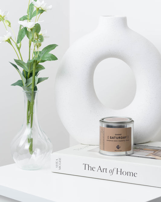 Soy wax candle with on a book next to a vase.
