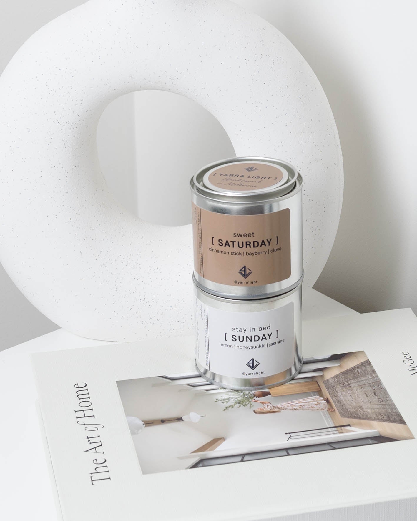 Two candles on a surface with a magazine underneath, against a light background