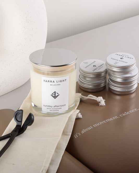 Yarra Light soy wax candle, sample candle tins and wick trimmer on a surface with a neutral background