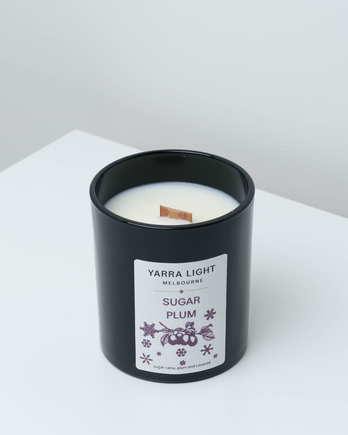 Sugar Plum Christmas soy candle in black glass with a wood wick and a plum label