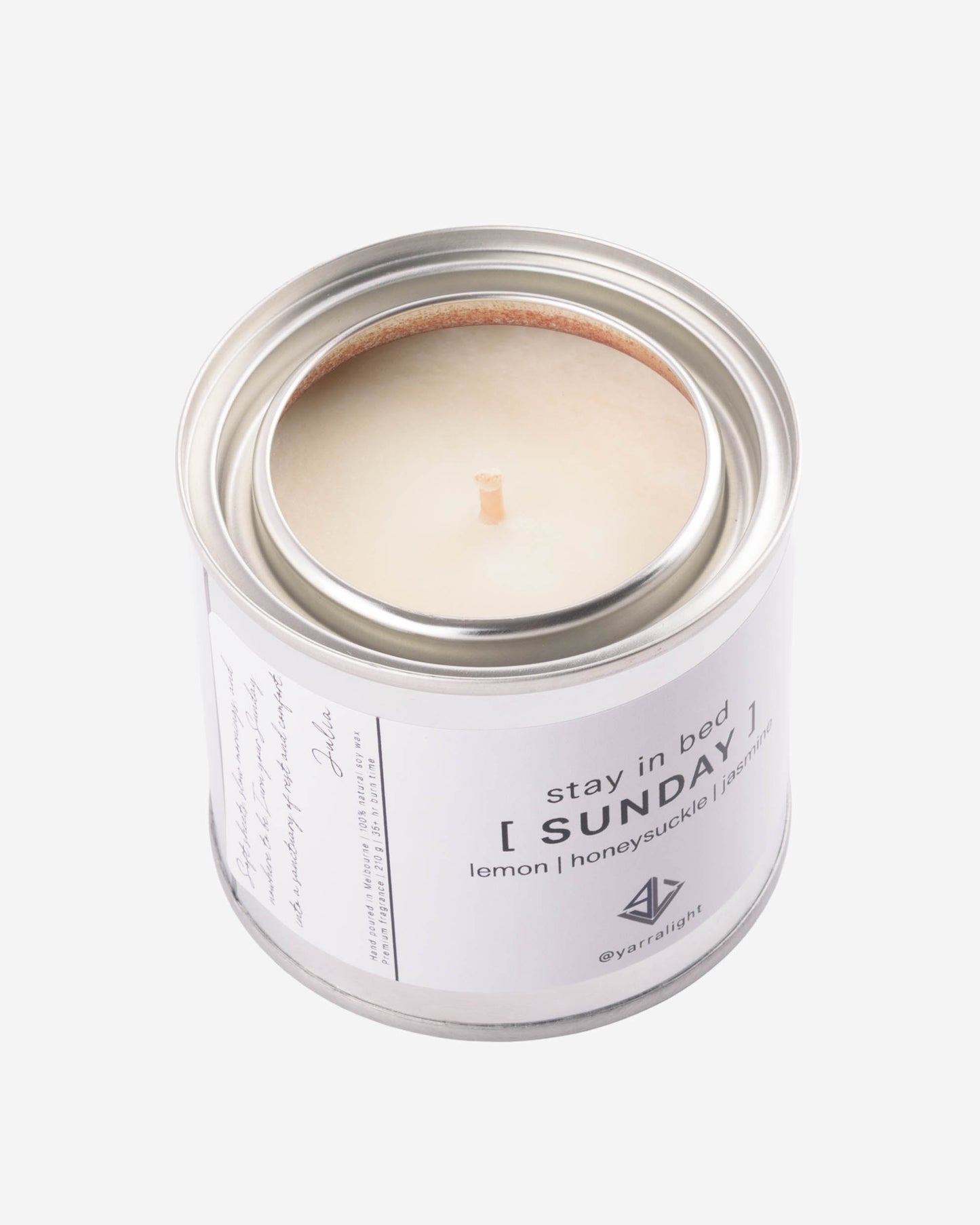 Hand poured soy wax candle in a metal container labeled 'Stay in Bed Sunday' on a white background
