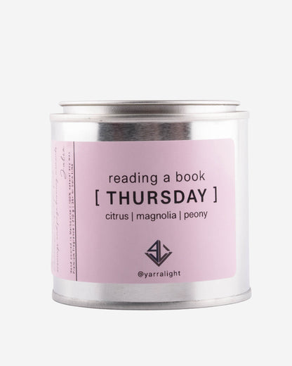 Candle tin labeled 'Thursday' with a pink label on a white background