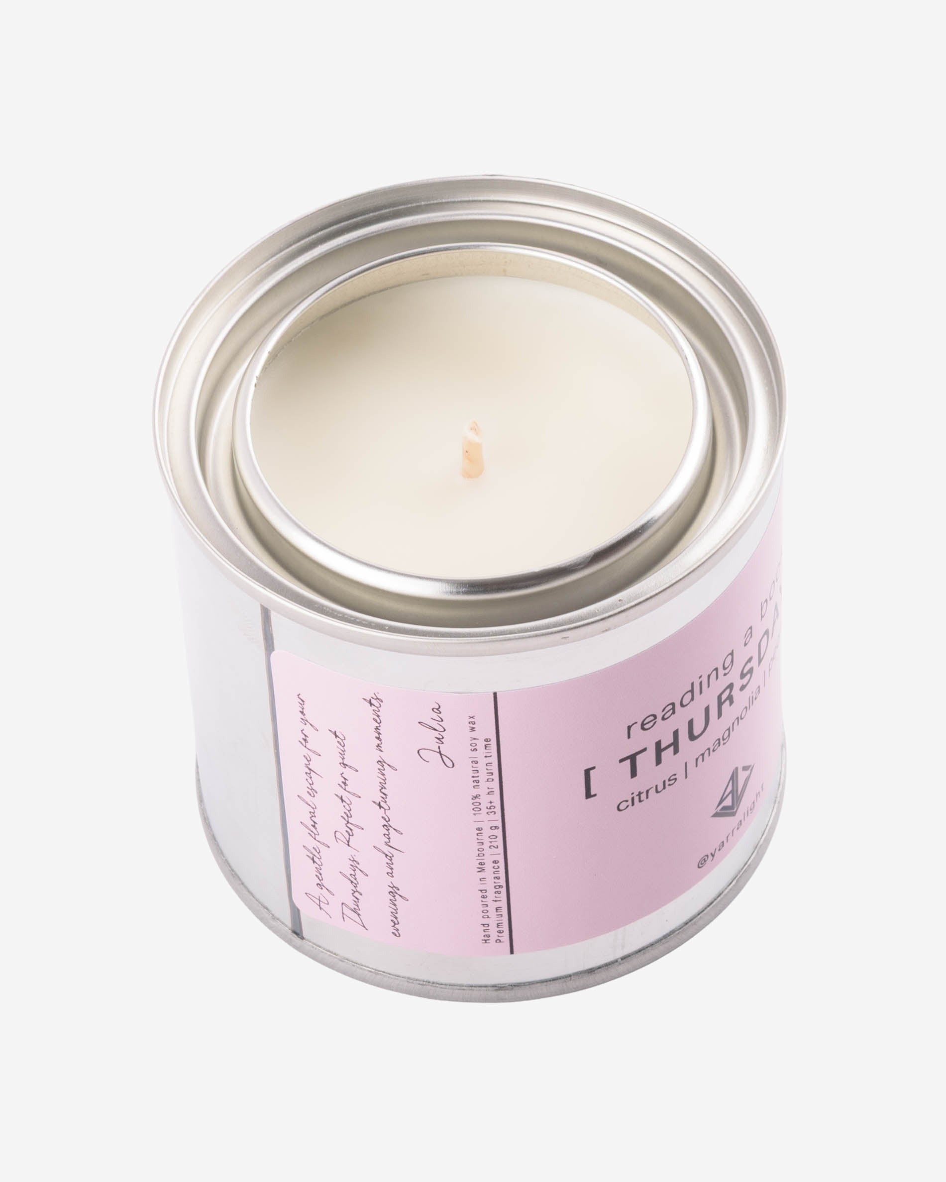Candle in a tin jar with a pink label on a white background