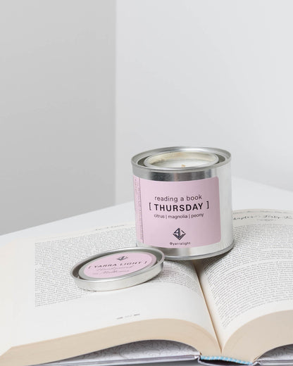 Candle labeled 'Thursday' on an open book .