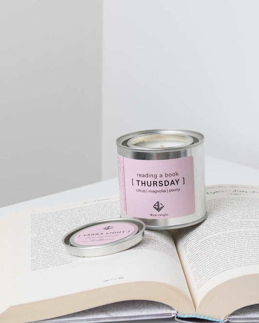 Candle labeled 'Thursday' on an open book .