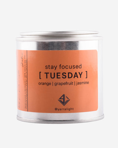 Candle tin with 'stay focused Tuesday' label on an orange background