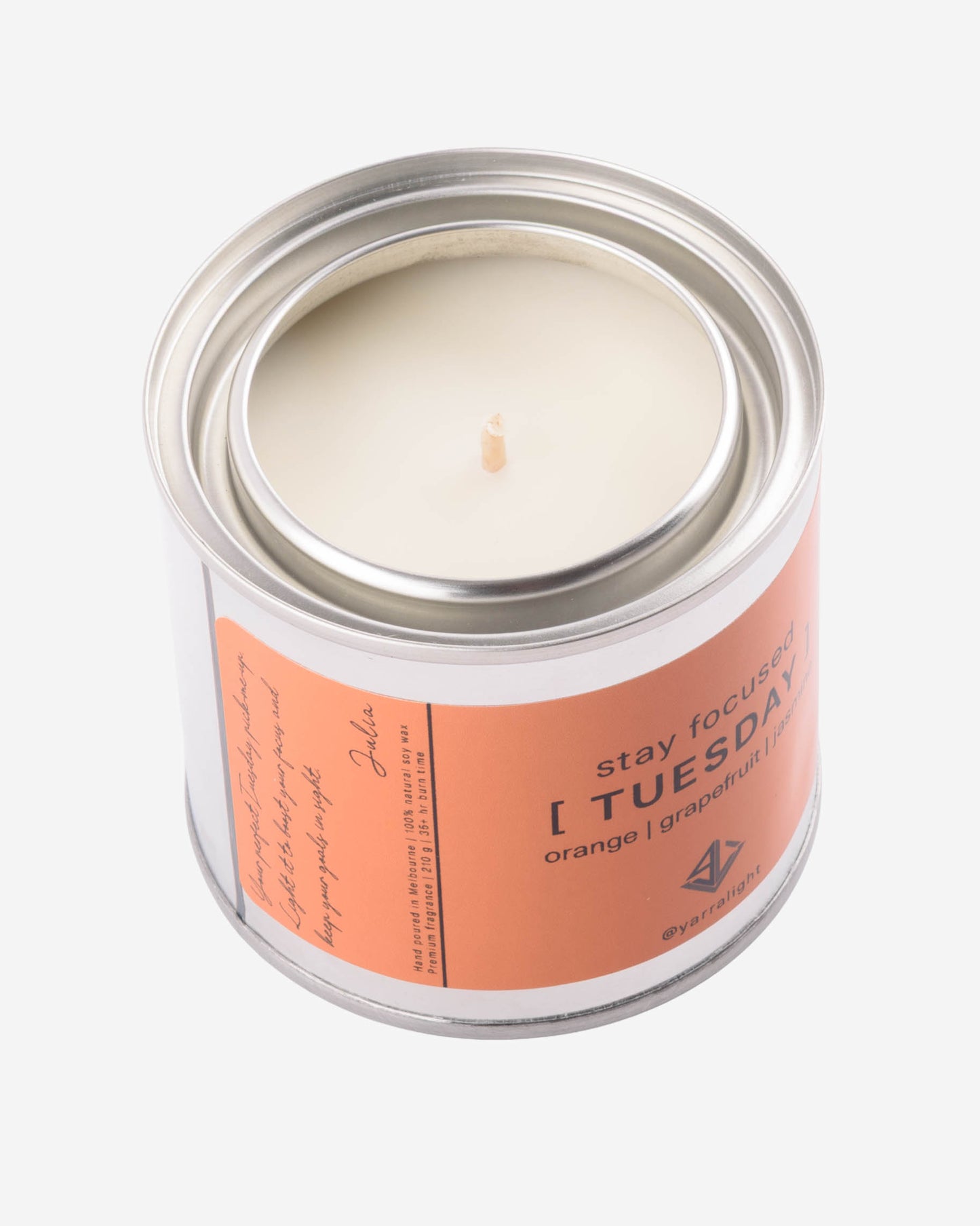 Candle in a glass jar with a peach-colored label on a white background