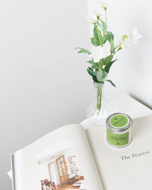 Soy wax candle on an open book with a vase of white flowers in the background