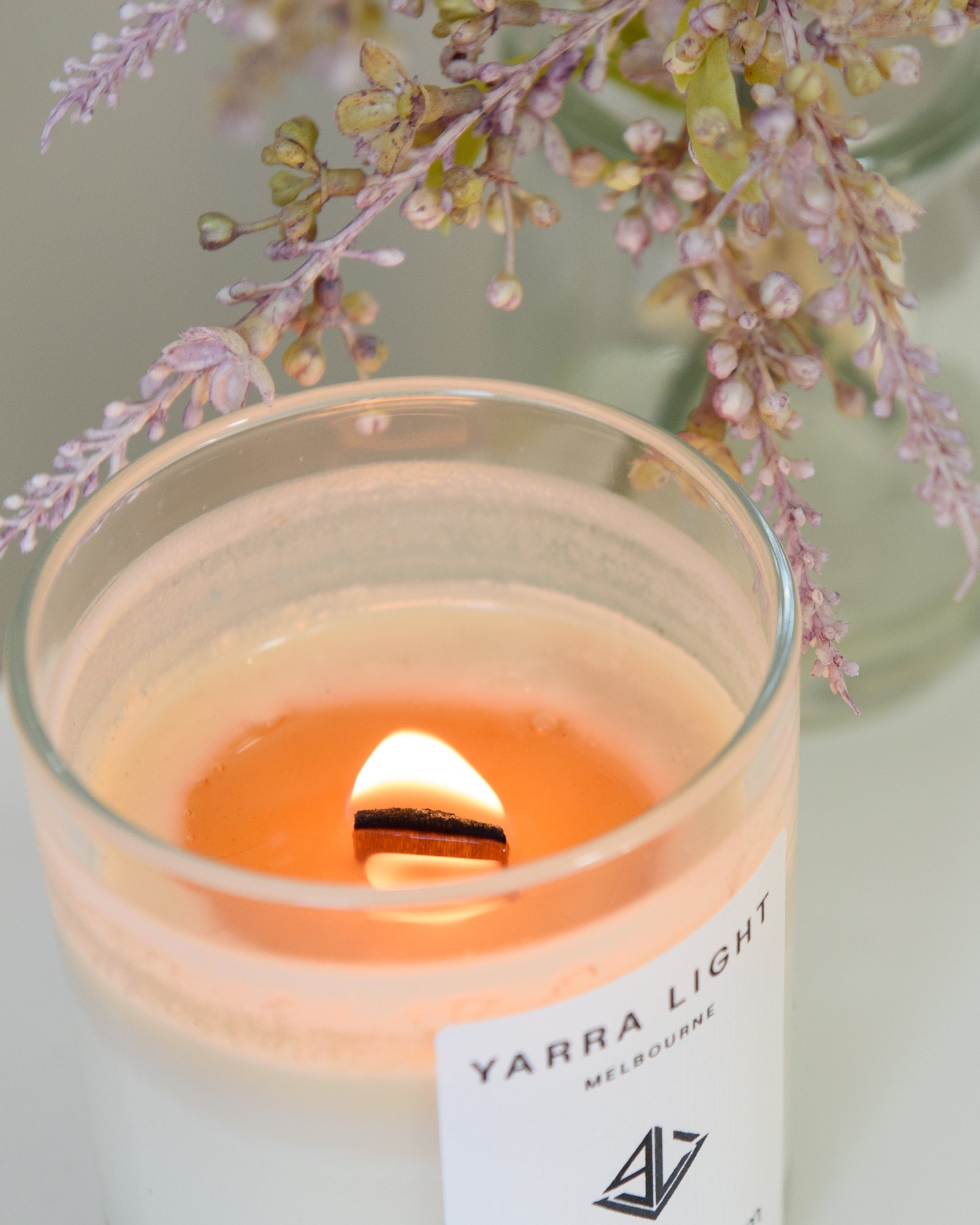 Yarra Light soy wax candle with a floral arrangement in the background